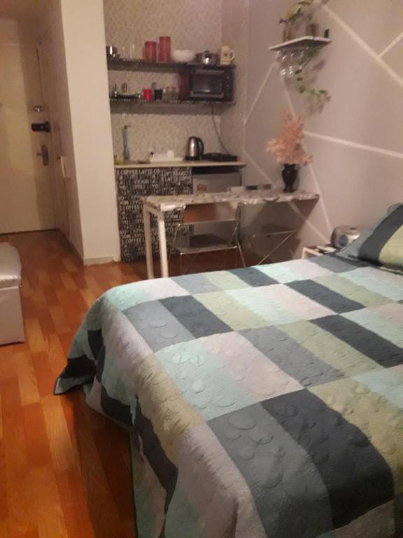 1 dormitorio con 1 cama con manta a cuadros en Monoambiente Completo en Bs As en Buenos Aires