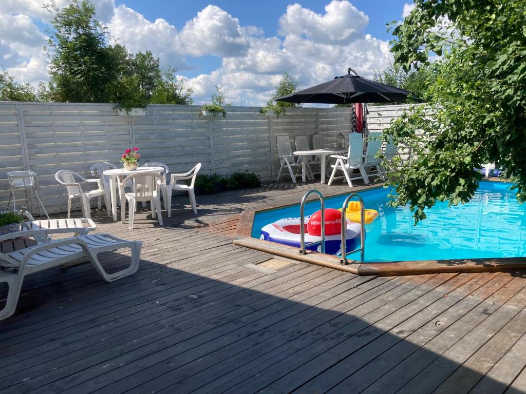 einen Pool mit einem Tisch, Stühlen und einem Sonnenschirm in der Unterkunft Mehri in Uppsala