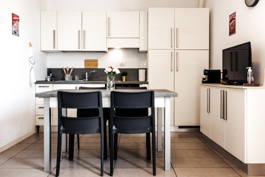 una cucina con armadi bianchi e tavolo con sedie di Casa R&R *10' a Piedi da Piazza Del Campo*! a Siena