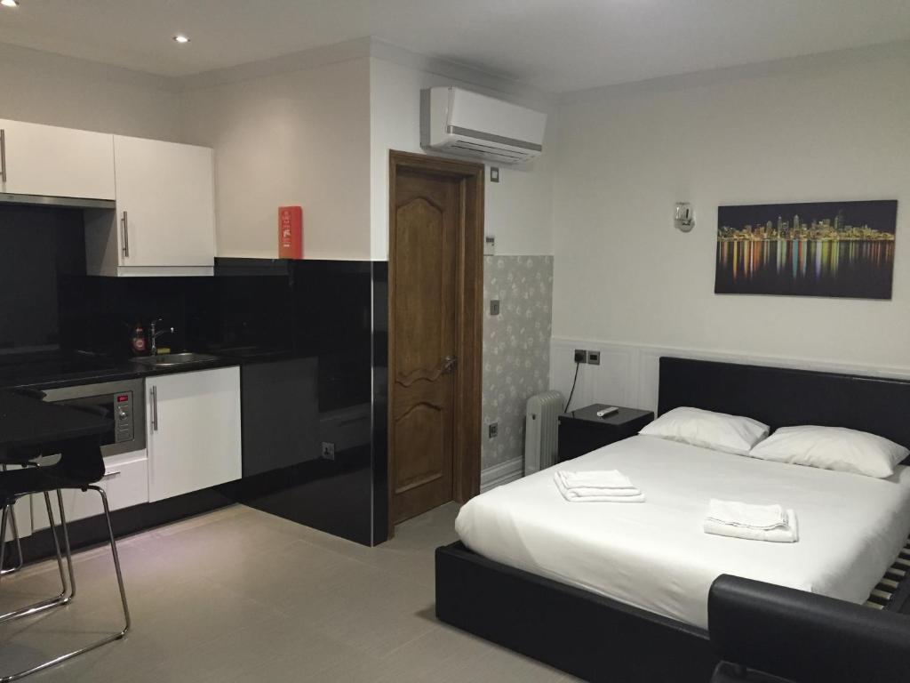 a bedroom with a white bed and a kitchen at Paddington Apartments in London