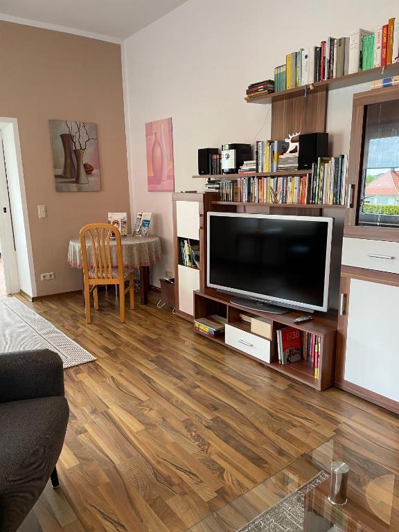 ein Wohnzimmer mit einem Flachbild-TV und Holzböden in der Unterkunft Ferienwohnung Martina in Blankenburg