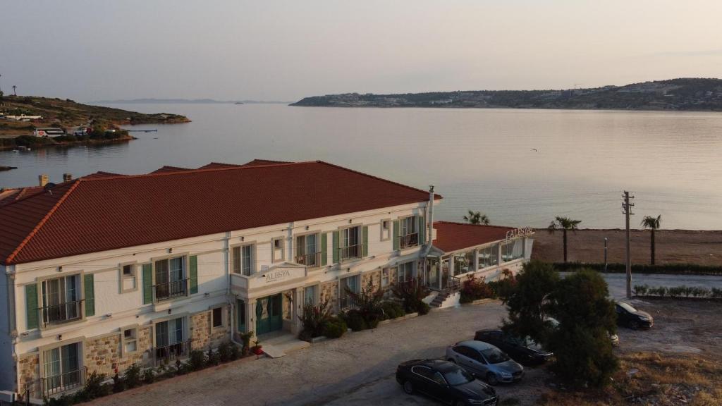 a building with cars parked in front of a body of water at Alesya Otel in Çiftlikköyü