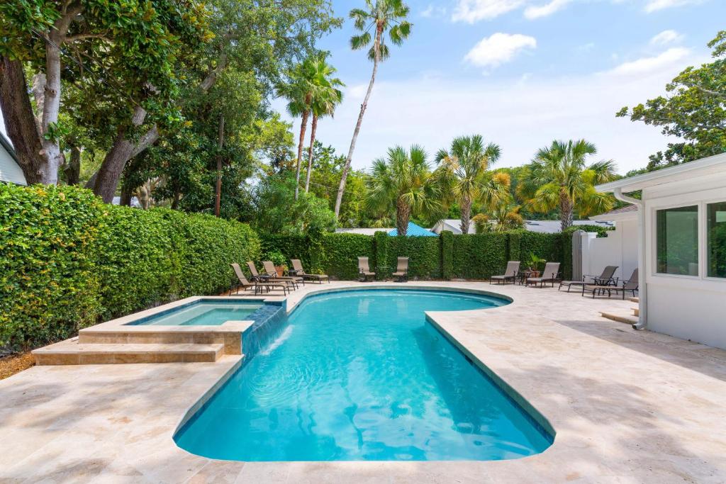 ein Swimmingpool in einem Hof mit Stühlen und Bäumen in der Unterkunft The Southern Whippoorwill - 4226 Fifth Street in Saint Simons Island