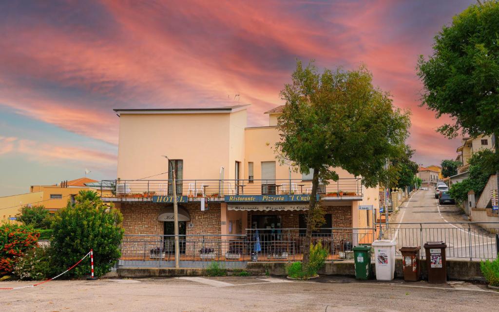 a building on a street with a cloudy sky at Hotel I Cugini in Castelfidardo