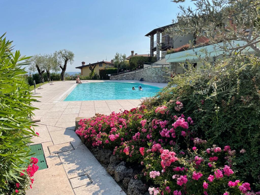 - une piscine avec des fleurs roses à côté d'une maison dans l'établissement Ferienwohnung Isabella, à Toscolano Maderno