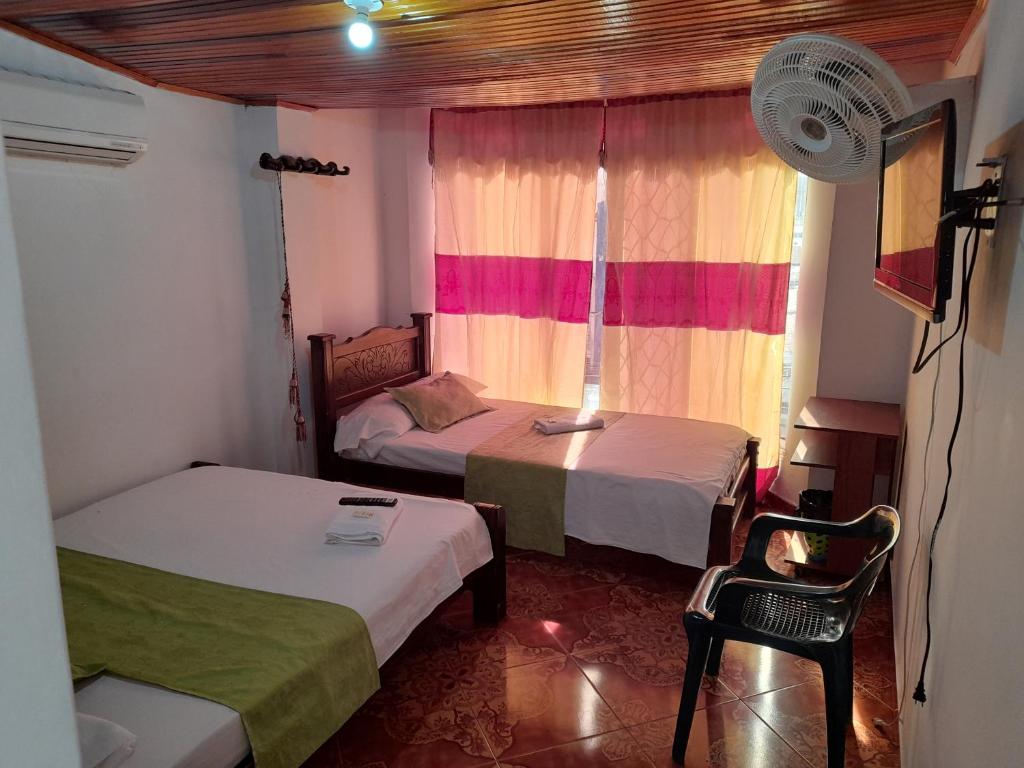 sypialnia z 2 łóżkami i oknem z wentylatorem w obiekcie HOTEL NUEVO SOL w mieście Florencia