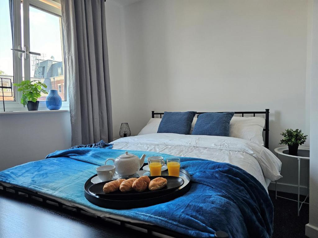 a tray of food on a bed with drinks and croissants at Spacious Two Bedroom Apartment with 2 En-suite Bathrooms in Northampton
