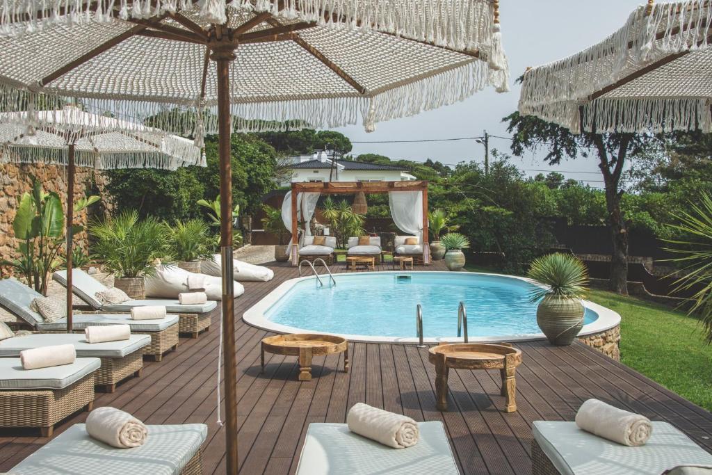 uma piscina com cadeiras e guarda-sóis em Villa Pietra Estoril Eco Guesthouse em Estoril