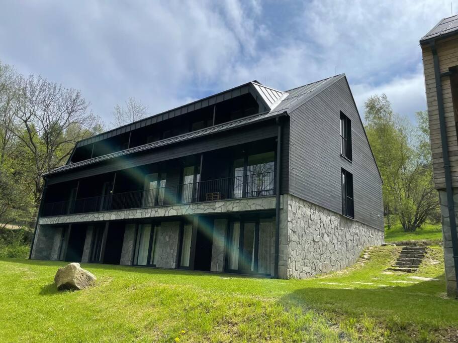 une grande maison avec une façade en pierre sur un champ verdoyant dans l'établissement Apartmán Harmonie - Šumava, à Frischwinkel