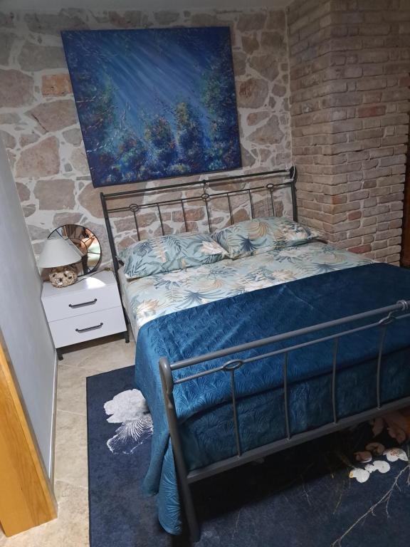 a bedroom with a bed and a painting on the wall at jardin kapetanova kuća in Veli Iž