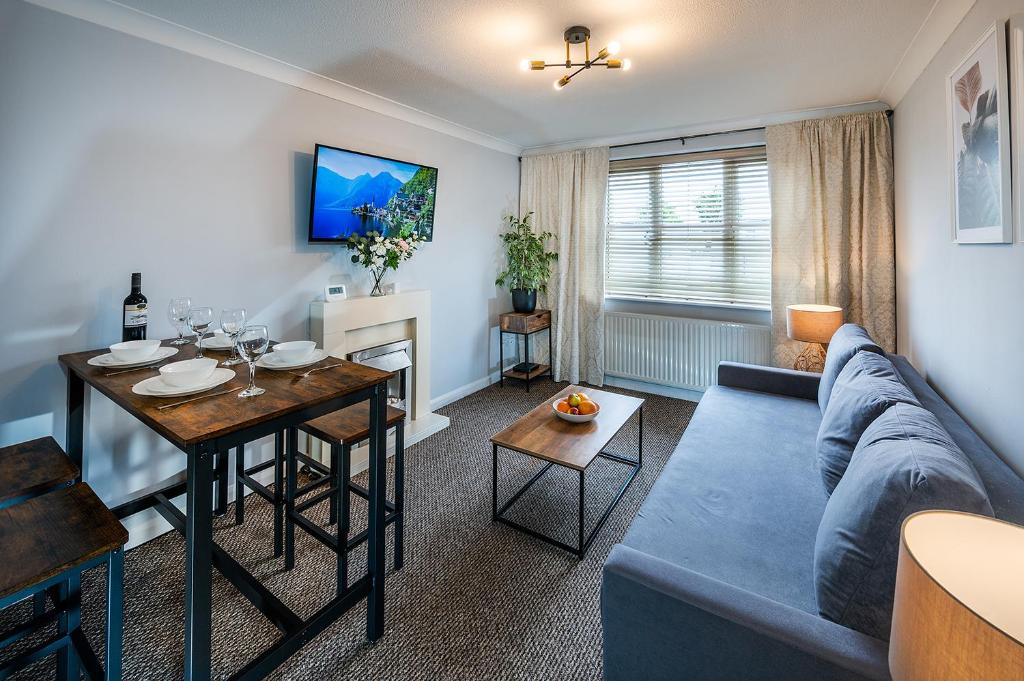 a living room with a blue couch and a table at Train Station Serenity in Staines upon Thames
