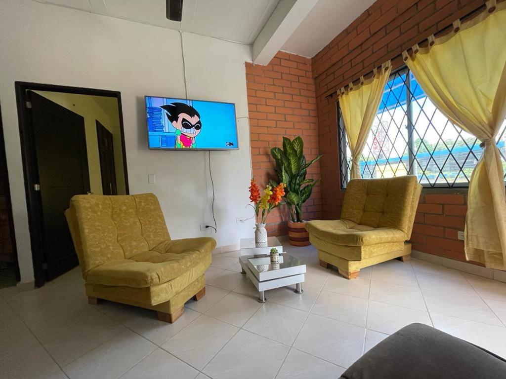 a living room with two chairs and a flat screen tv at Apartamento acorde para una estadía tranquila. in Apartadó