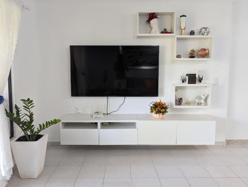 un centro de entretenimiento blanco con TV de pantalla plana en la pared en Apartamento a 5 min de la playa, en San Felipe de Puerto Plata