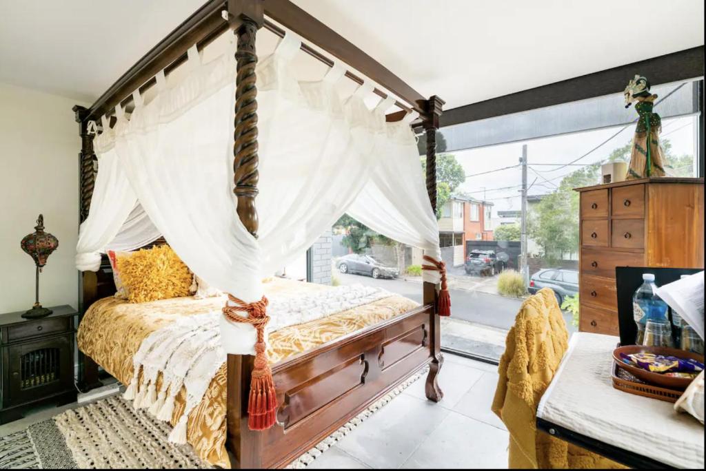 sypialnia z łóżkiem z baldachimem i oknem w obiekcie Bayside Boutique Retreat- Black Rock, Melbourne. w mieście Black Rock North