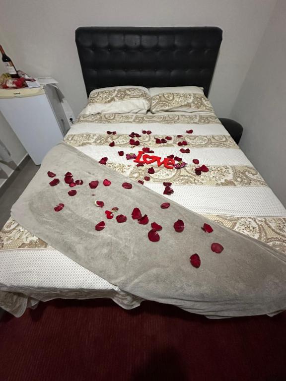 Una cama con pétalos rojos sobre una manta blanca en Pousada Recanto dos Pássaros en Lindóia