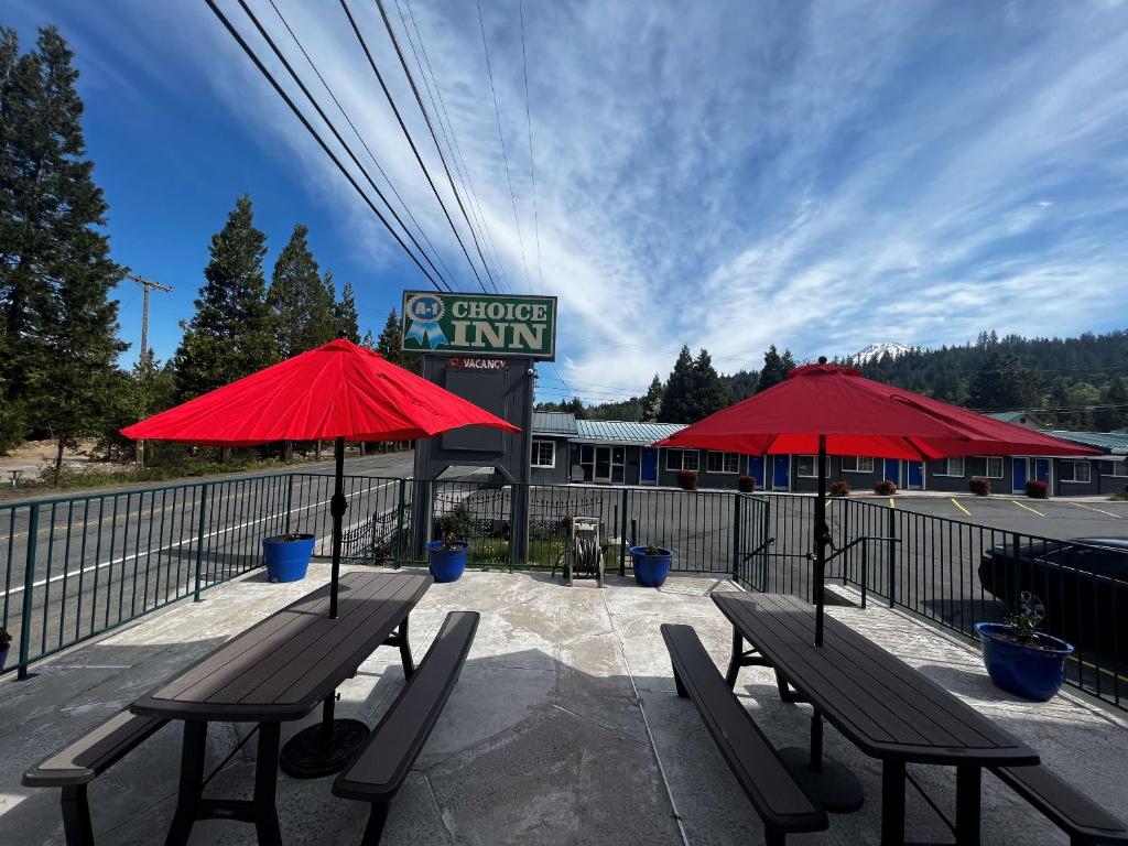two benches and red umbrellas in front of a building at A1 Choice Inn in Mount Shasta
