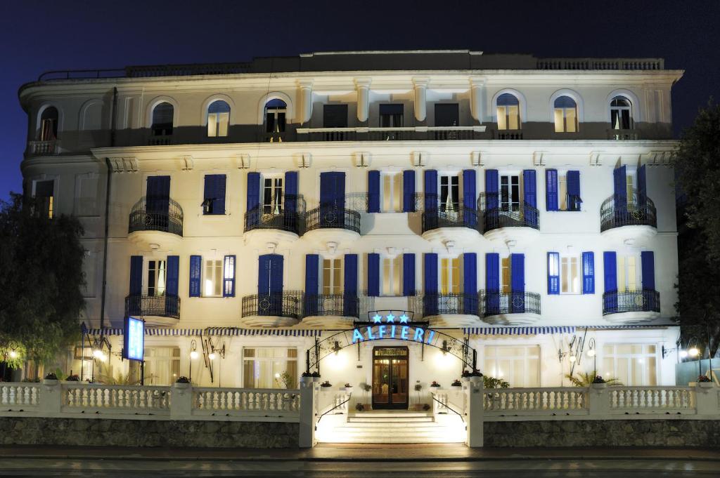 a large white building with blue shutters at night at Hotel Alfieri in Alassio