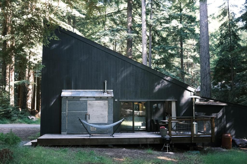 a black house in the woods with a bench at Modern House w. Fast Internet in 1 Acre Land in Occidental