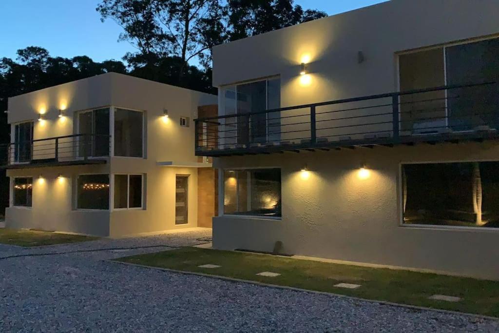 Casa para 4 personas en vista24uy, Bella Vista, Maldonado في بيلا فيستا: منزل أبيض كبير مع شرفة في الليل