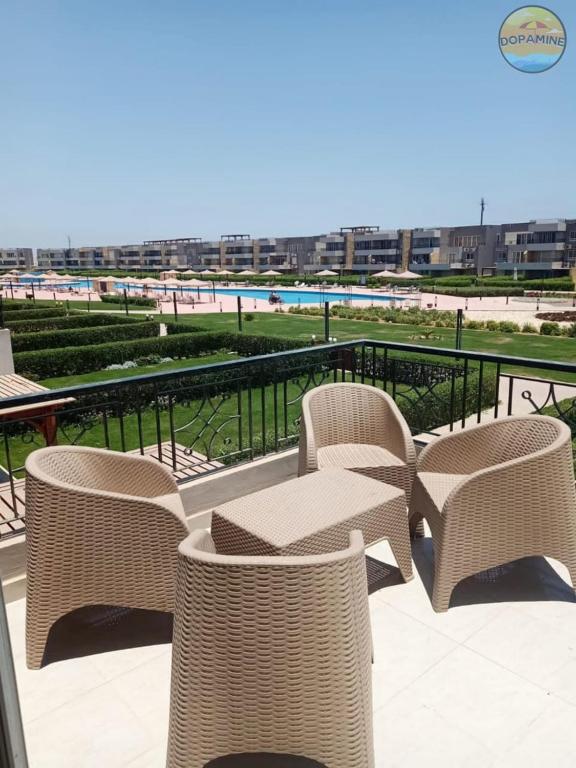 a group of wicker chairs and tables on a patio overlooking a beach at Blumar El Sokhna Chalet in Ain Sokhna