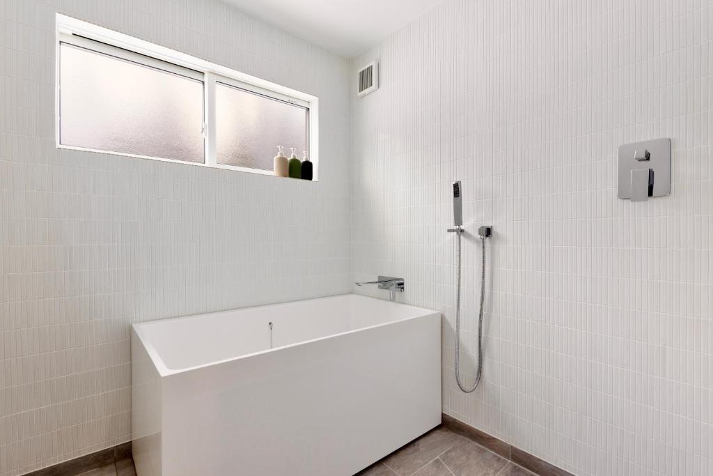 un bagno bianco con lavandino e finestra di Piccolo House a Hakuba