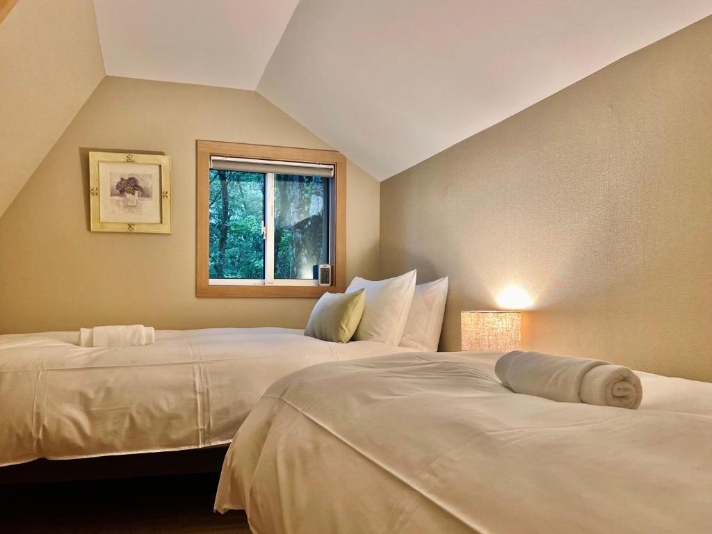 2 letti bianchi in una camera con finestra di Piccolo House a Hakuba
