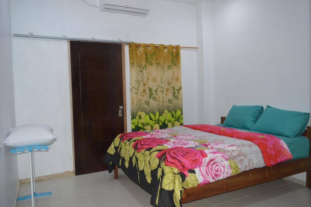 a bedroom with a bed with a colorful blanket at Mahoni Guest House Labuan Bajo in Labuan Bajo