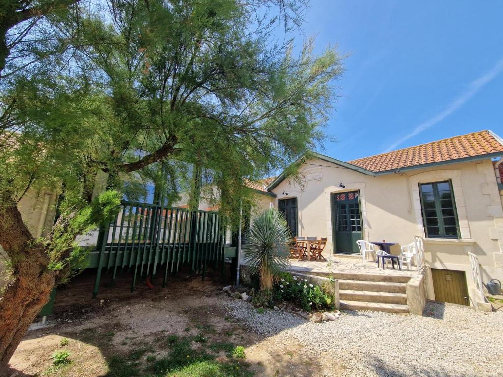 une maison avec une clôture et un arbre dans l'établissement Charmante Villa 4 pièces, 6 pers. au Quartier du Casino de Châtelaillon-Plage, proche mer, jardin, parking - FR-1-706-15, à Châtelaillon-Plage