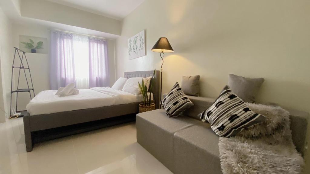 a bedroom with a bed and a couch at Luxury Suites at Brenthill Baguio City in Baguio