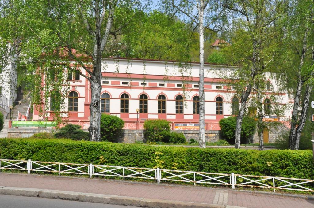 een roze gebouw met een hek ervoor bij Hostel Děčín Na Skřivánce in Děčín