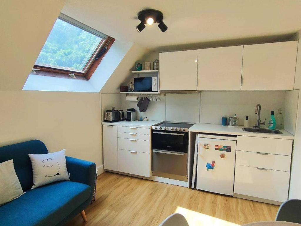 une petite cuisine avec des placards blancs et un canapé bleu dans l'établissement Duplex 2 pièces près des télécabines avec parking, idéal pour 4 personnes - FR-1-234-307, à Cauterets