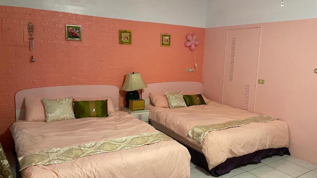 冬山鄉的住宿－夆閣沅民宿，配有粉红色墙壁的客房内的两张床