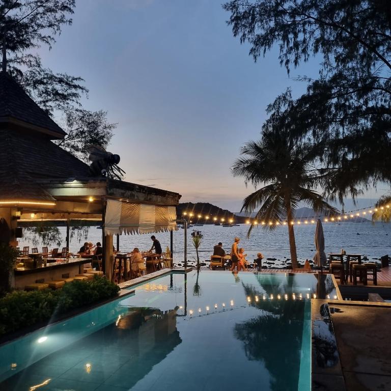 a swimming pool with a view of the ocean at night at Samui Honey Backpacker Bungalow in Choeng Mon Beach