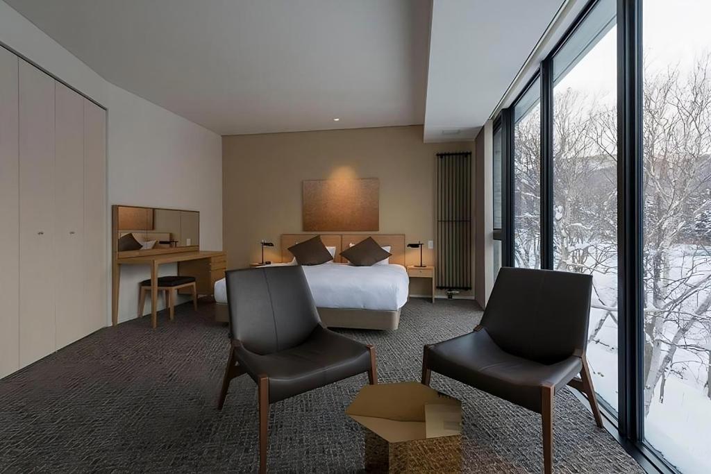 a hotel room with a bed and two chairs at Kozue in Niseko