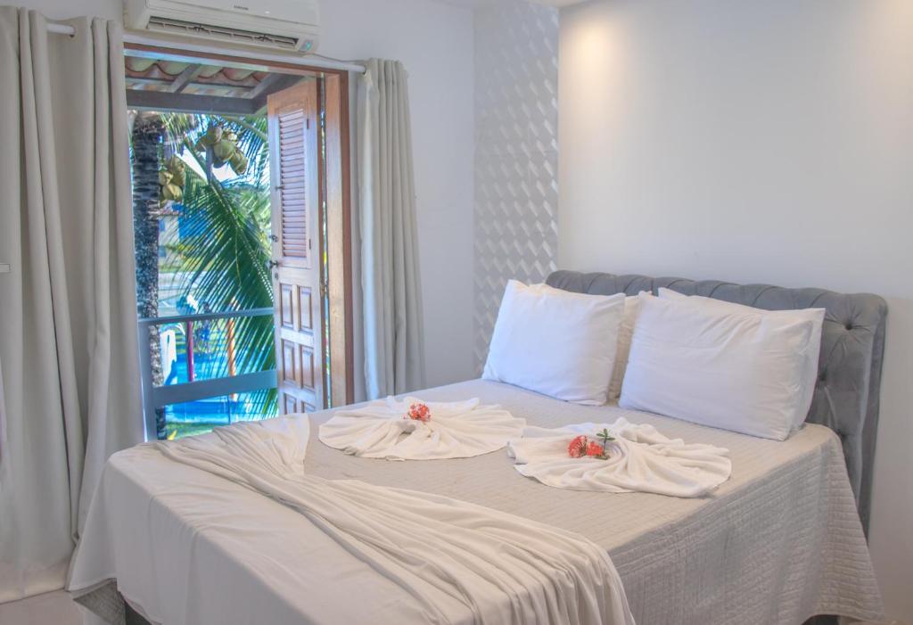 a bed with two towels on it with a window at Apto a 300m da praia AxéMoi in Porto Seguro