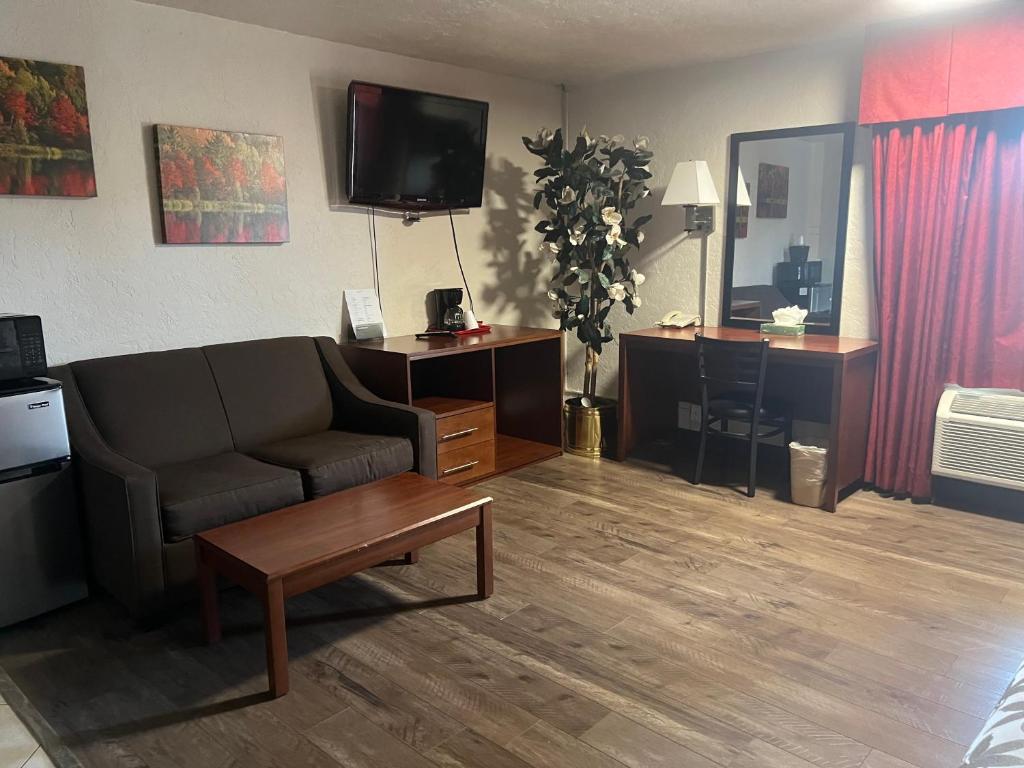 a living room with a couch and a tv at Red Carpet Inn Medford in Medford