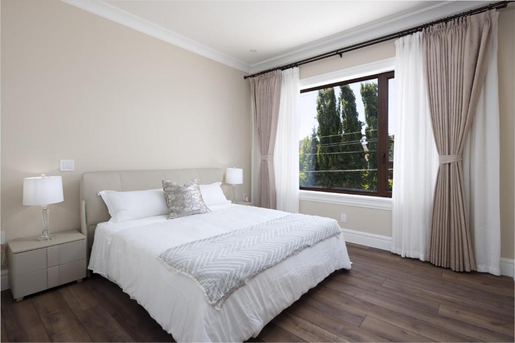 a white bedroom with a bed and a window at Vancouver Vacation Home in Richmond