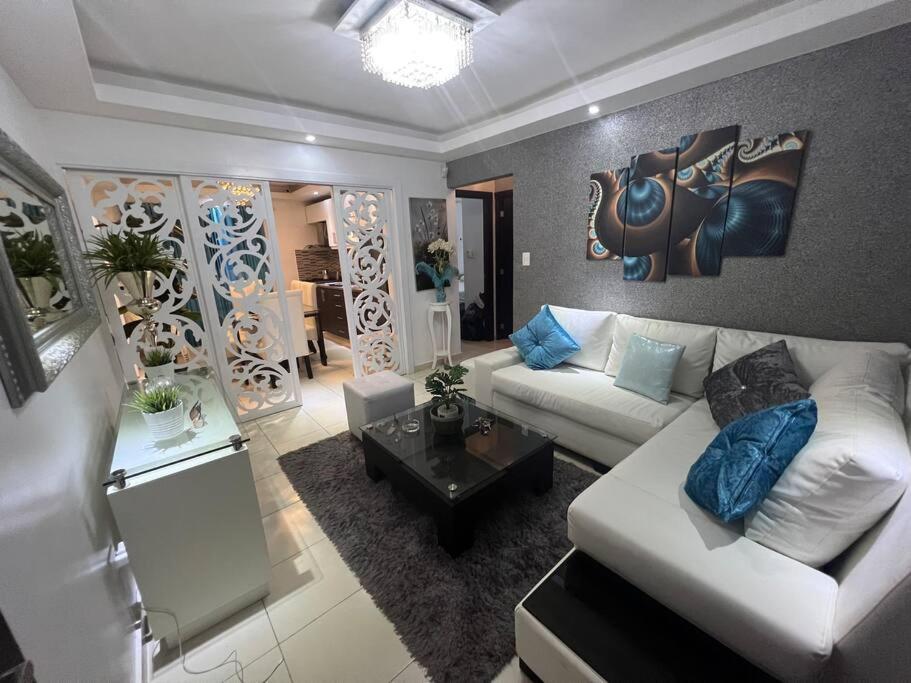uma sala de estar com um sofá branco e almofadas azuis em Apartamento amueblado. em Santiago de los Caballeros