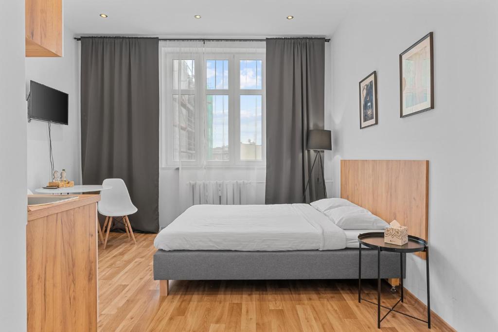 a bedroom with a bed and a table and a desk at Apartamenty Centrum Zameldowanie 24h in Katowice