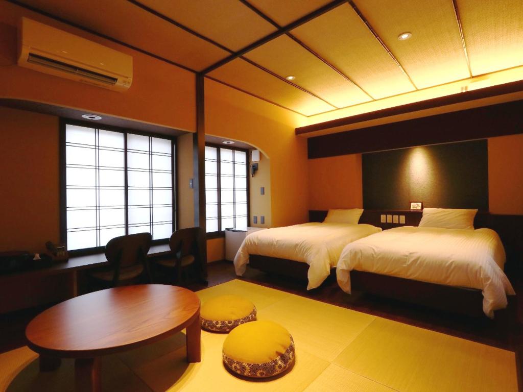 a hotel room with two beds and a table and a table at Kii no Matsushima in Kihokucho