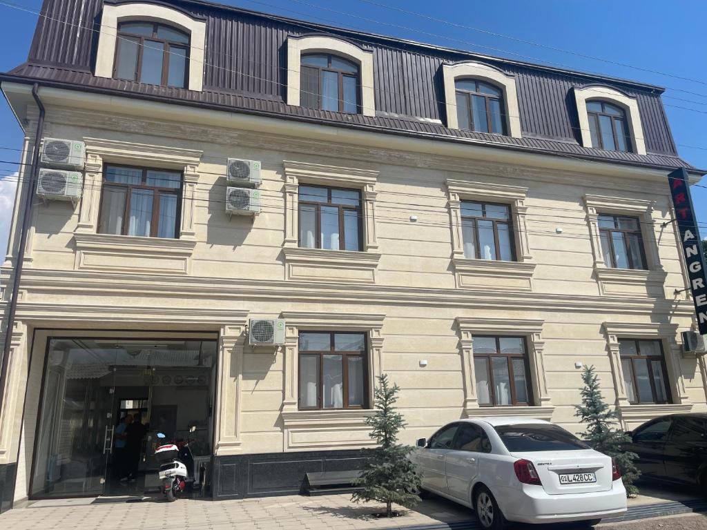 a building with a car parked in front of it at Art Angren Hotel in (( Sotsgorod ))
