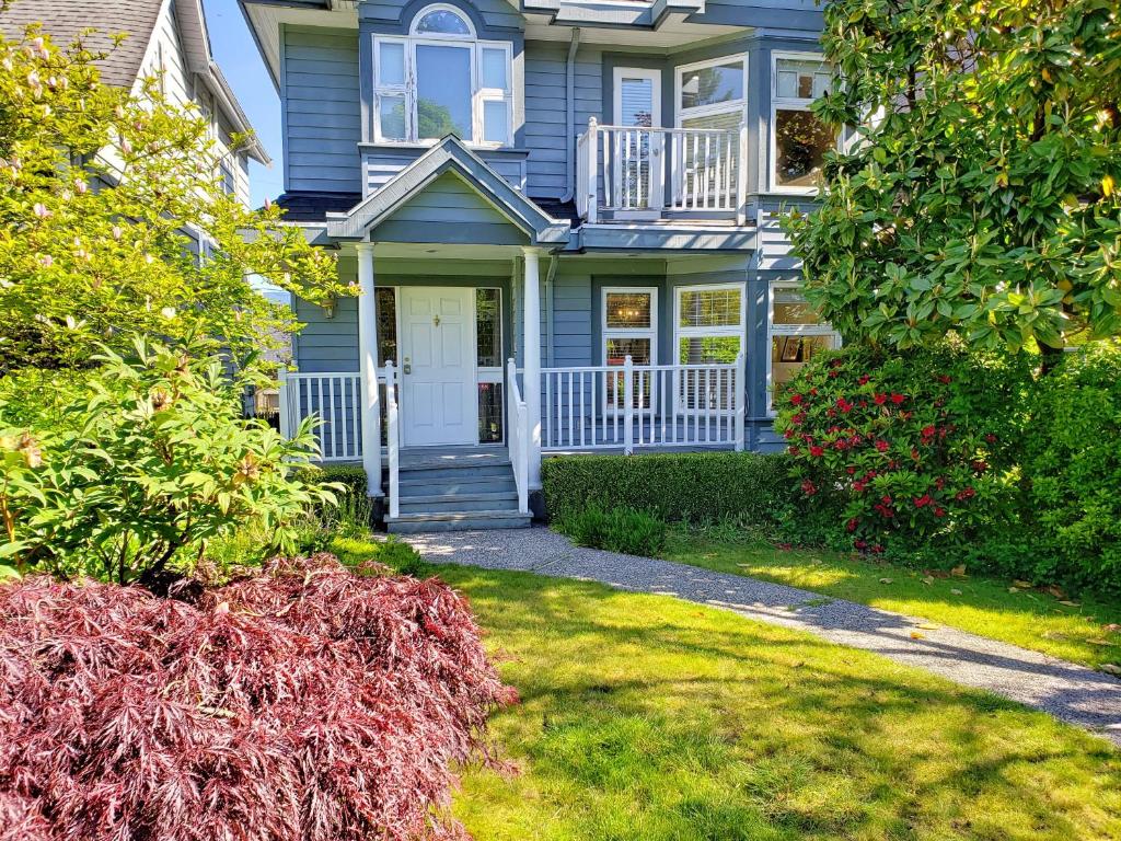 a blue house with a porch and a yard at Bright Garden Suite by the Beach and UBC in Vancouver