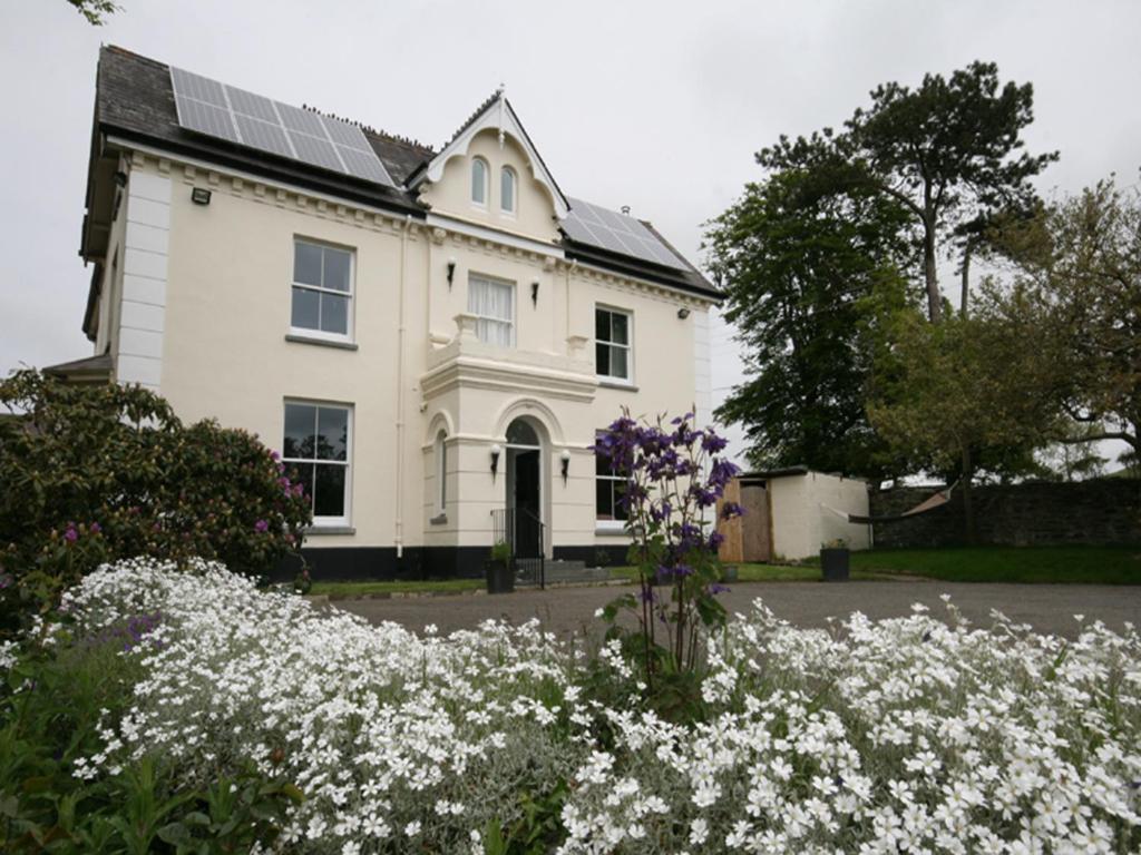 una casa con muchas flores delante de ella en Caemorgan Mansion en Cardigan