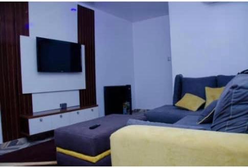a living room with a bed and a flat screen tv at Dee Rocket in Ibadan