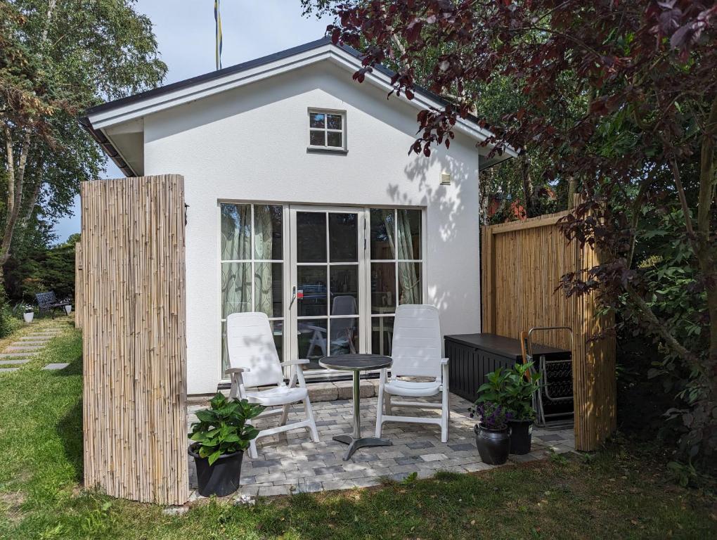 ein kleines Haus mit einem Tisch und Stühlen auf einer Terrasse in der Unterkunft Cute little cottage in Höllviken in Höllviken