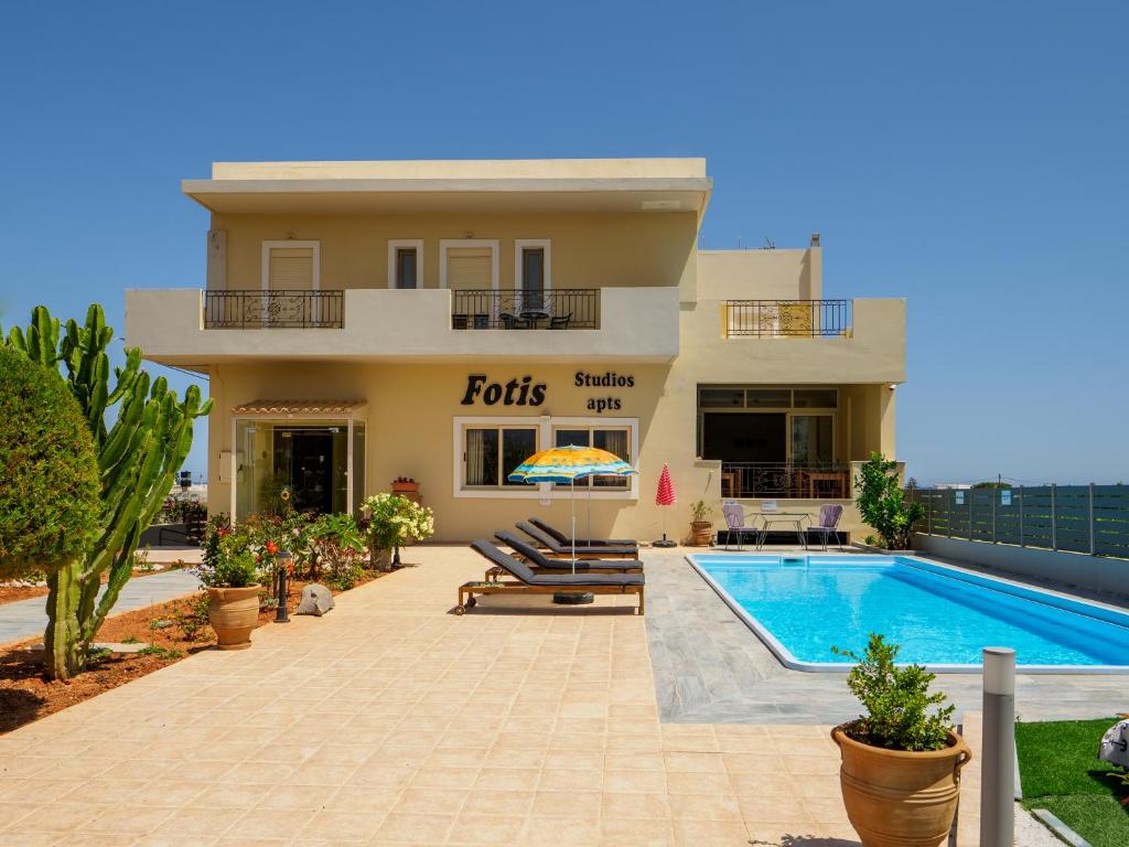 una casa con piscina frente a ella en Fotis Studios Apartments en Gouves