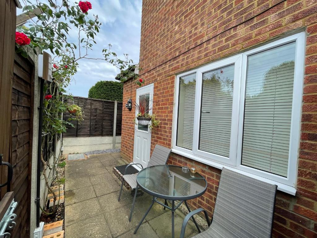 a small patio with a glass table and chairs at Studio-2 Staines,Heathrow, London-own entrance in Staines