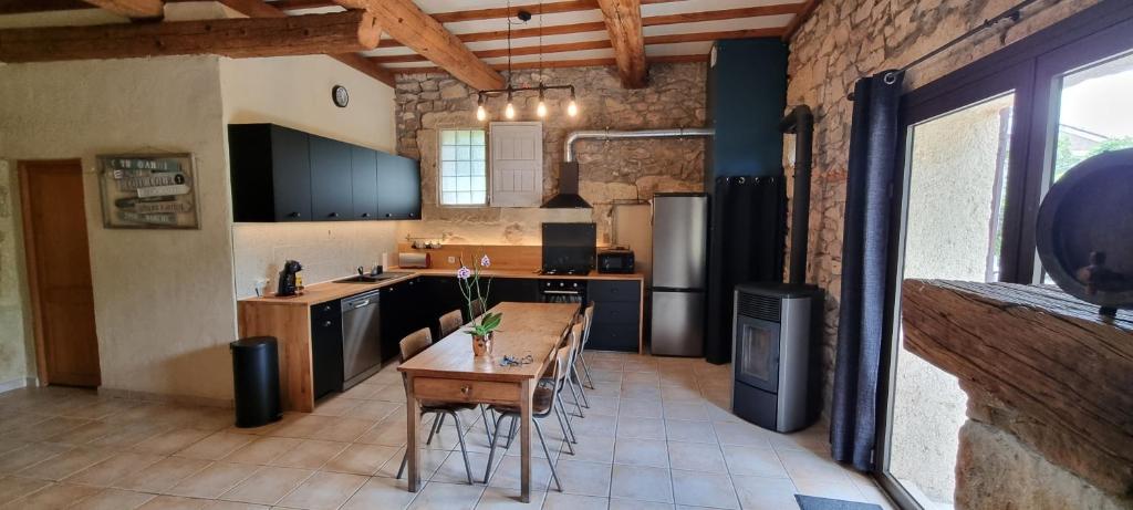 een grote keuken met een houten tafel en stoelen bij La Grangette Grange rénovée 100m2 terrasse privative,10 min mer in Villeveyrac