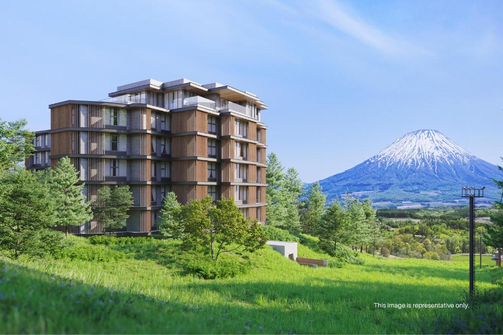 a building on a hill with a mountain in the background at Niseko Kyo in Niseko