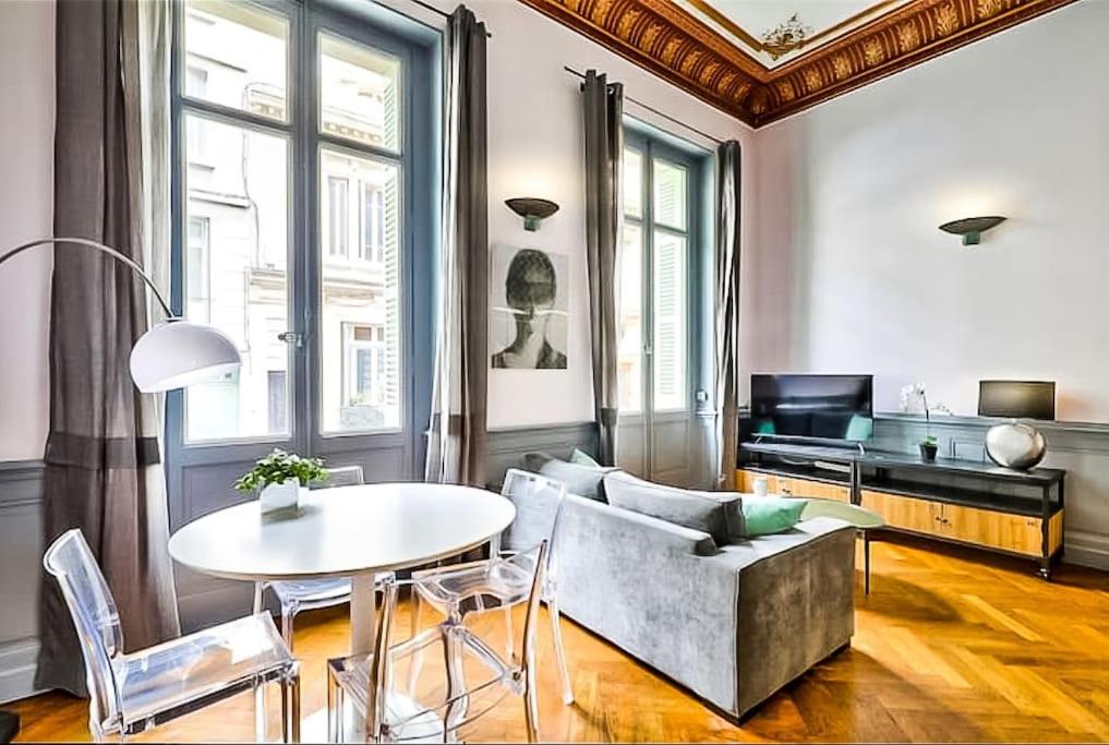a living room with a table and a couch at Appartement Chic & Baroque avec parking sécurisé in Avignon